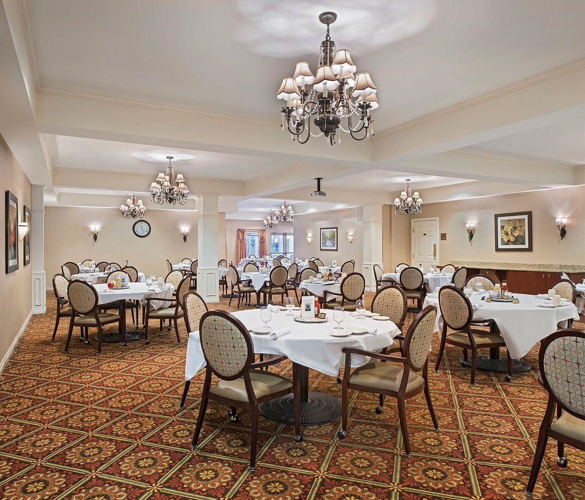 An elegant dining room with chandeliers and neatly arranged tables.