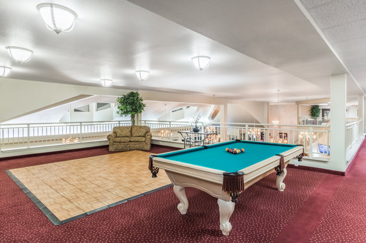A well-lit game room featuring a pool table and comfortable seating.