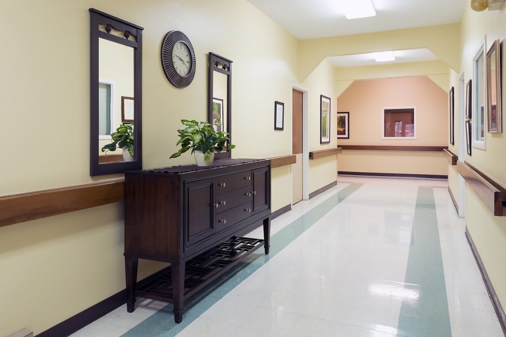 A well-decorated hallway with mirrors, a clock, and a wooden cabinet.