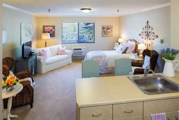 A cozy and well-decorated studio apartment with a bed, sofa, and various furnishings.