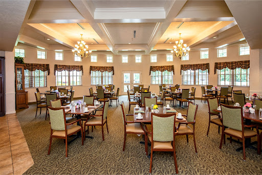 A spacious dining room featuring elegant tables and chairs, illuminated by beautiful chandeliers.