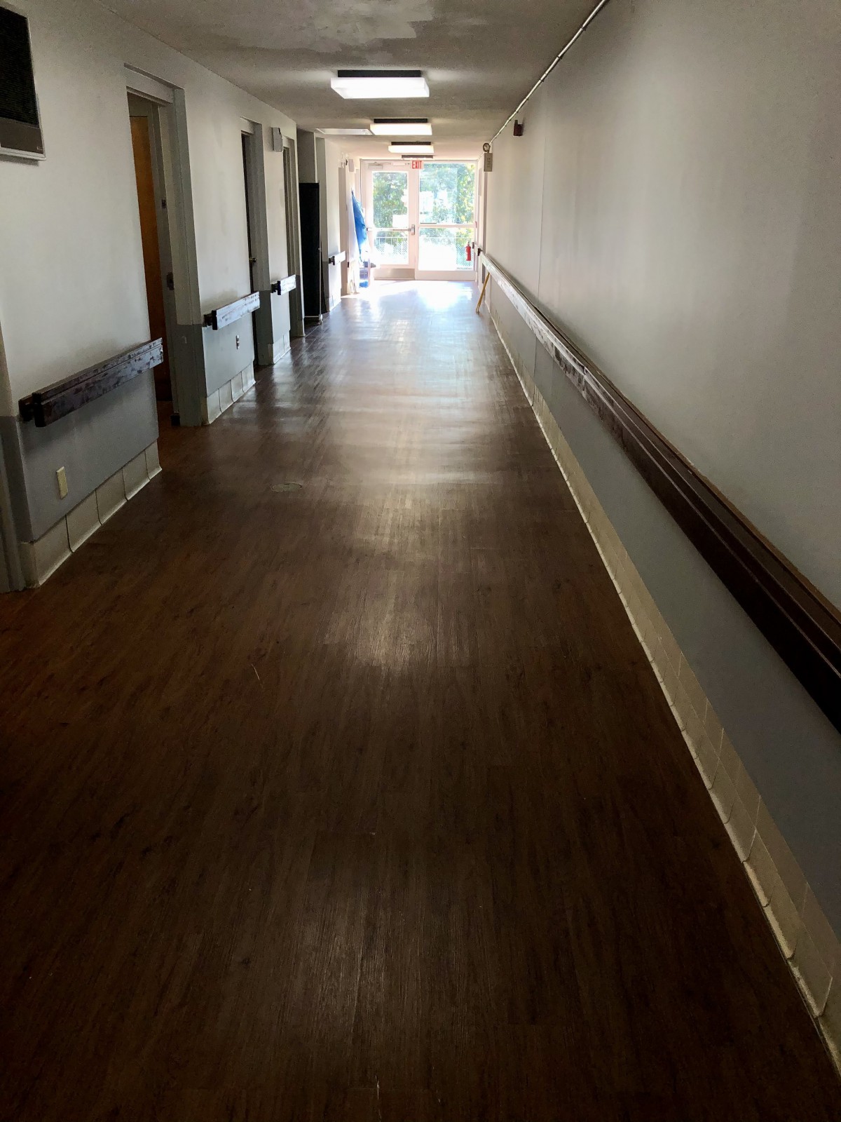An empty hallway with wooden flooring and handrails on the walls.