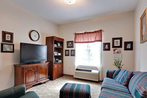 A cozy living room with a television, bookshelf, and comfortable seating.