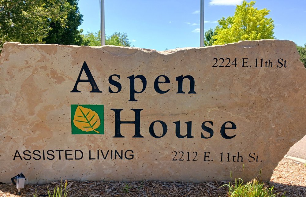 A stone sign for Aspen House Assisted Living with an address displayed.