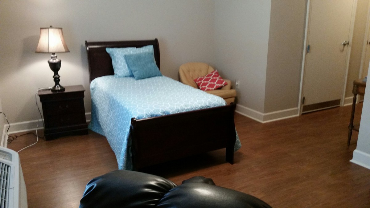 A cozy bedroom with a single bed adorned with blue bedding, accompanied by a chair in the corner.