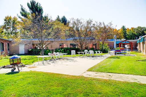 A serene outdoor area featuring green lawns, trees, and a poolside relaxation zone.