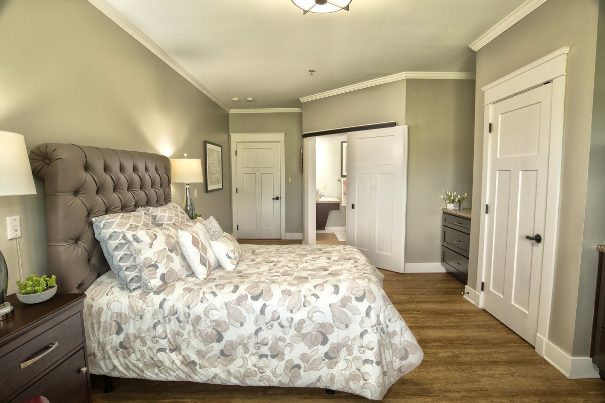A cozy and elegantly designed bedroom with neutral colors and wood flooring.