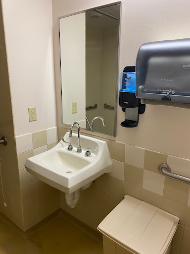 A clean bathroom featuring a sink, mirror, and hand dryer.