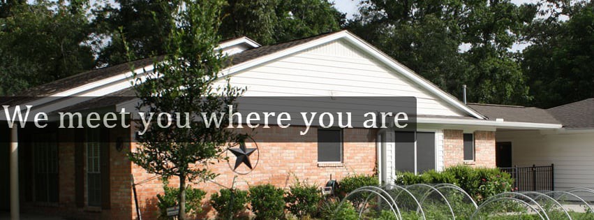 A brick house with a garden and decorative star, featuring the text 'Bloom where you are planted.'