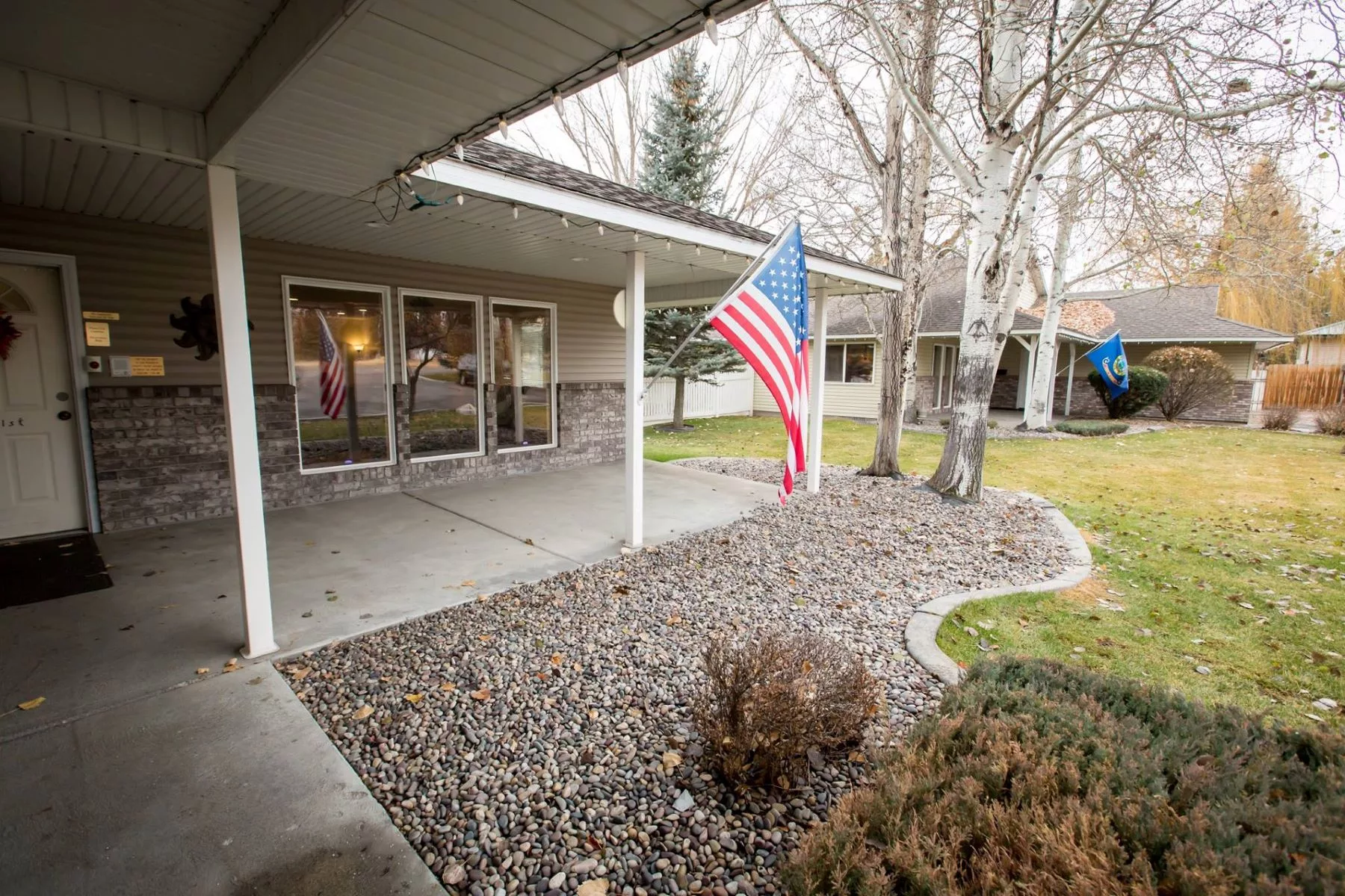 A suburban house with a patio featuring an American flag and garden.
