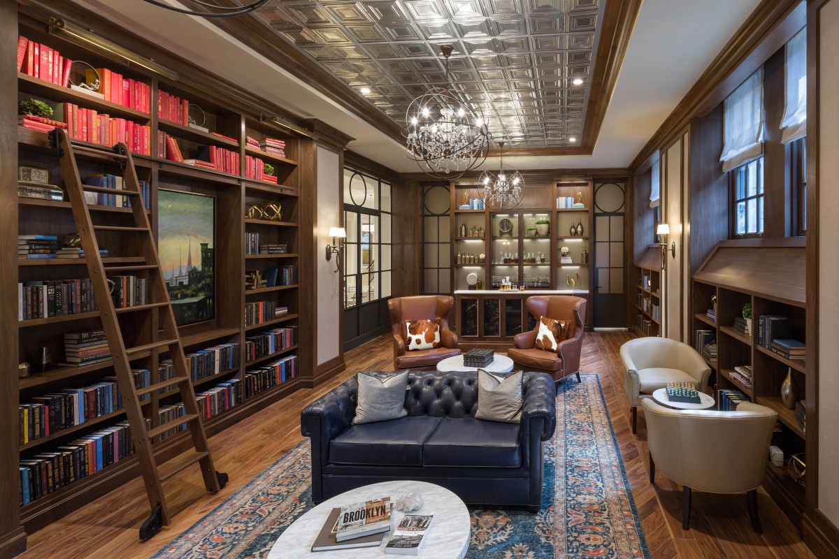 A luxurious library with leather armchairs, a sofa, and extensive bookshelves under a decorative ceiling.