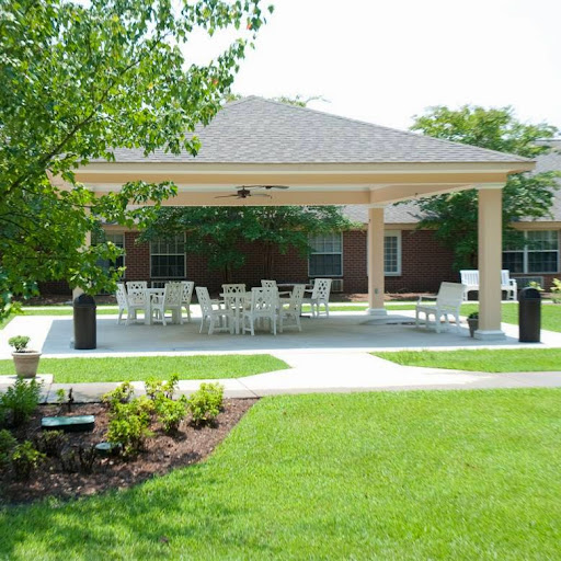 A serene outdoor pavilion with seating, surrounded by lush greenery.