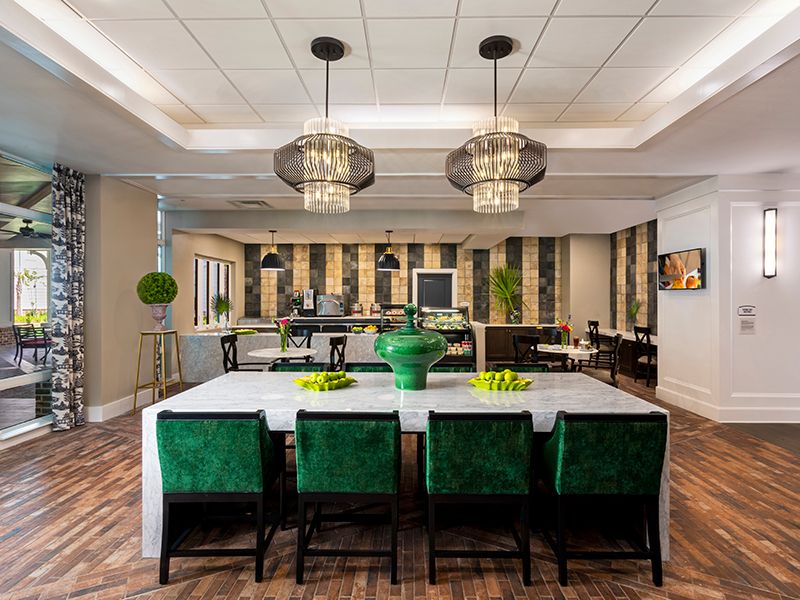 Modern dining area with elegant green chairs and stylish chandeliers.
