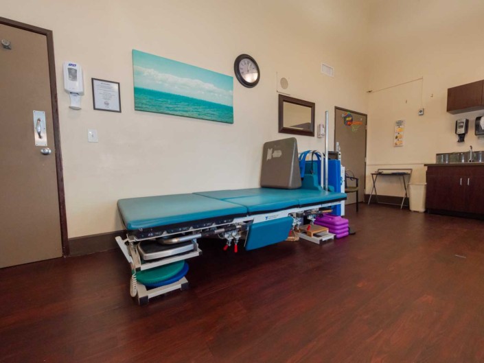 A physical therapy room equipped with a treatment table and exercise equipment.