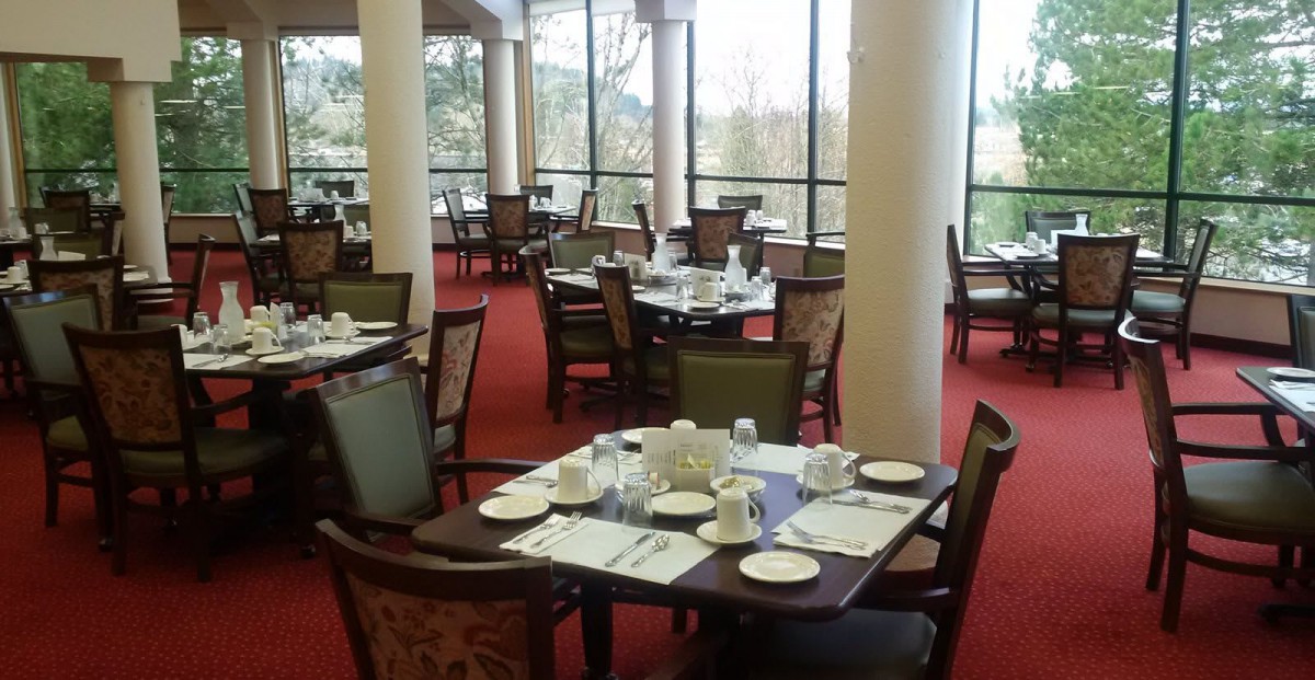 An indoor dining area with neatly set tables and large glass windows.
