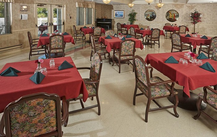 A cozy restaurant dining area with tables covered in red tablecloths and elegant chairs.