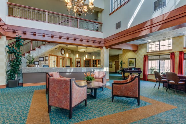 A spacious hotel lobby with elegant furniture and a central chandelier.