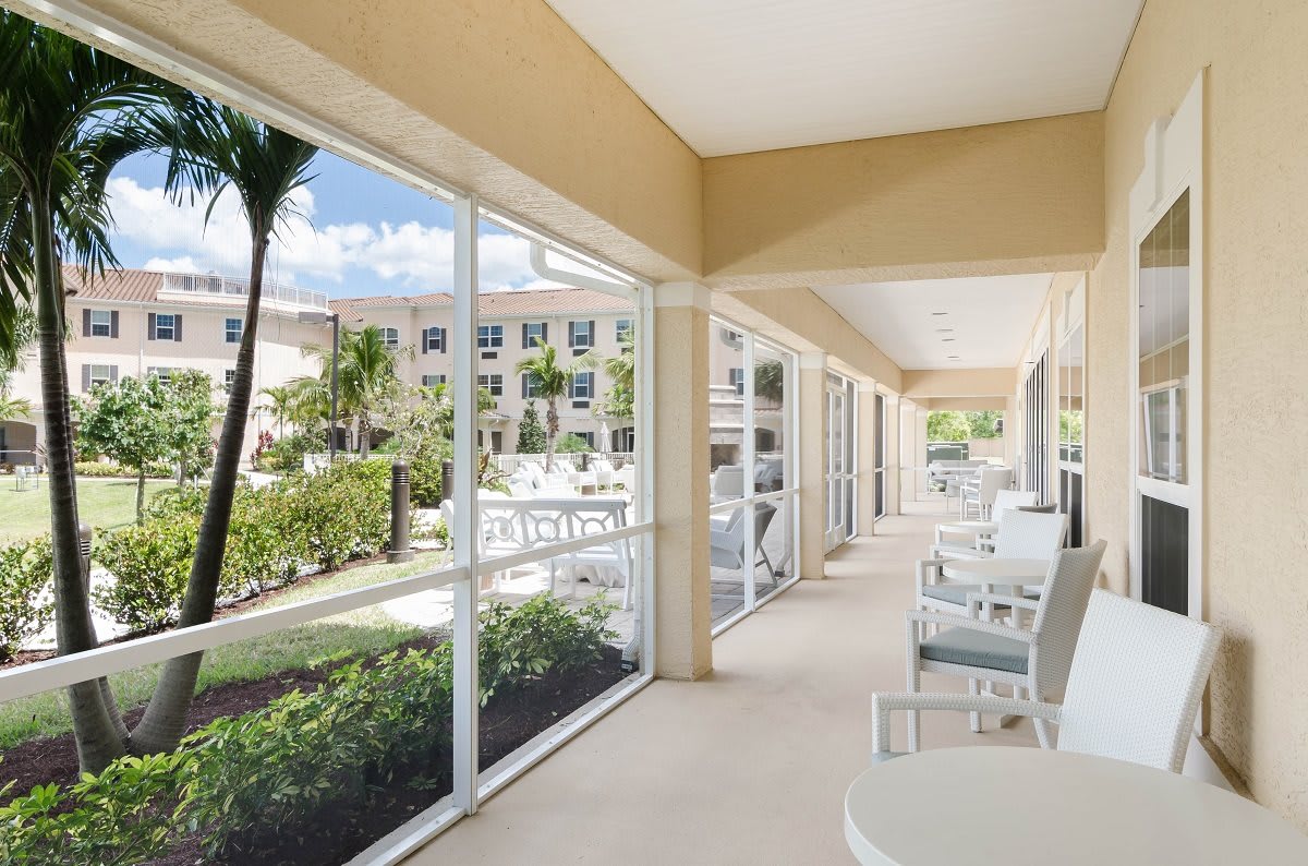 A bright hotel corridor with outdoor seating and garden views.