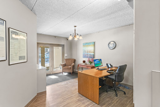 A modern office space featuring a wooden desk, comfortable seating, and ample natural light.