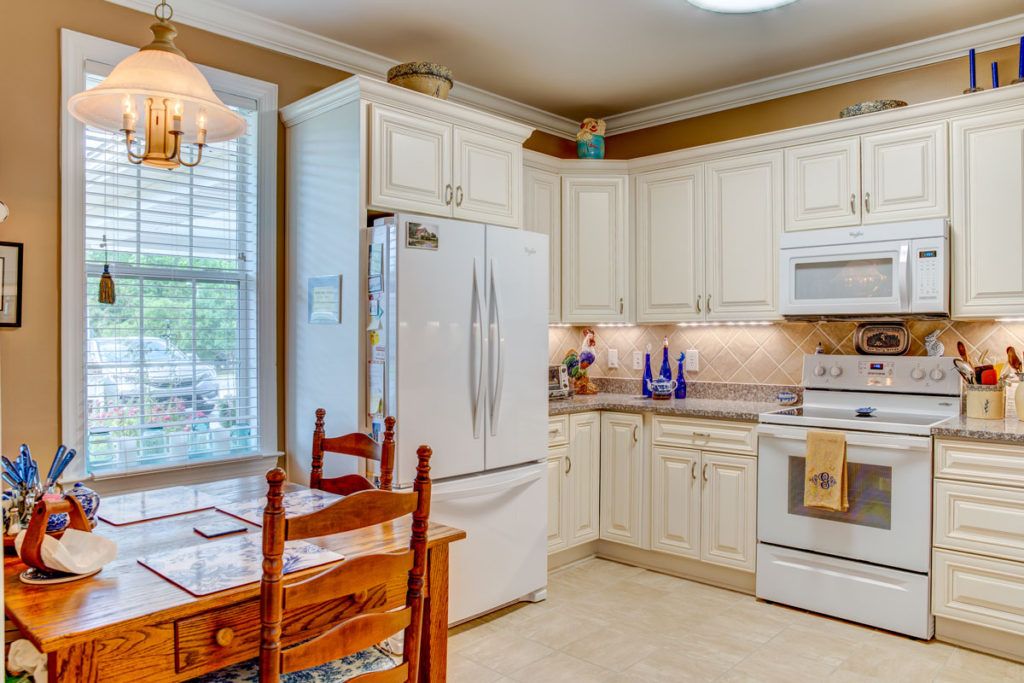 A cozy kitchen with white cabinetry, a dining area, and modern appliances.