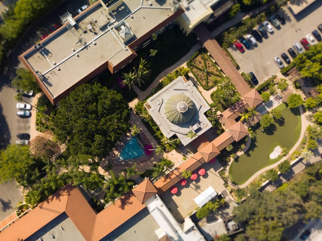 An aerial view of a complex featuring buildings, a garden, and a parking lot.