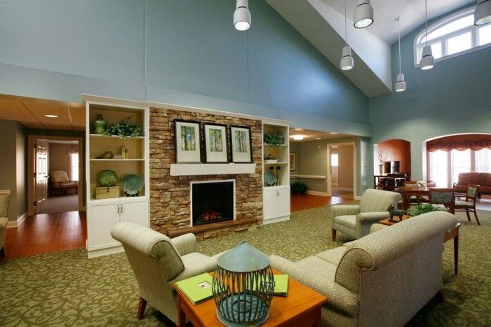 A cozy and modern living room with a fireplace, sofas, armchairs, and decorative shelves.