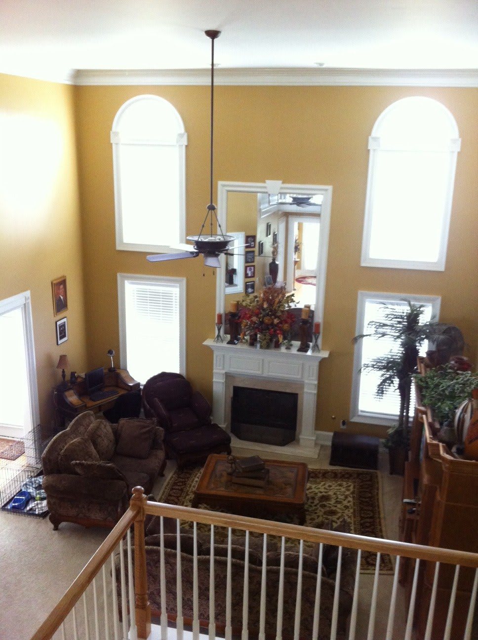 A spacious living room with a high ceiling, featuring large windows, a fireplace, and comfortable seating.
