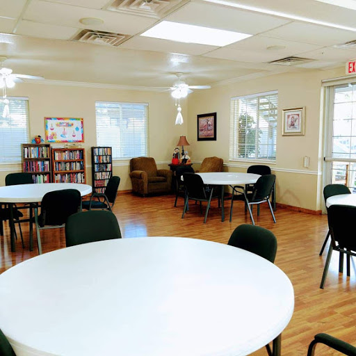 A spacious community room featuring round tables and comfortable seating, designed for gatherings and activities.