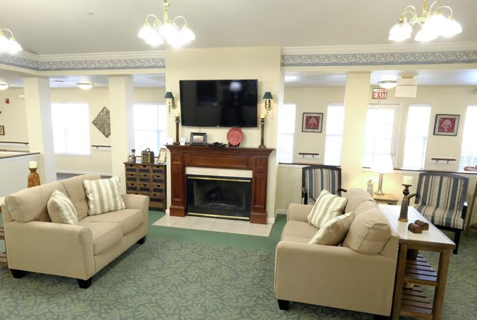 A cozy living room with sofas, a fireplace, and a television mounted above.