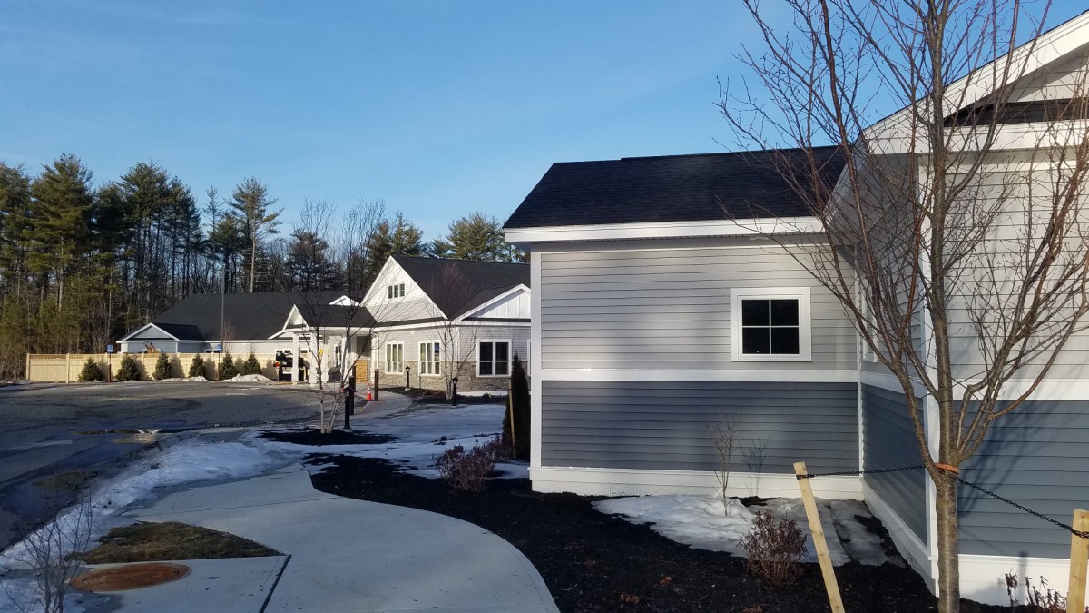 A quiet residential area with houses and light snow under a clear blue sky.