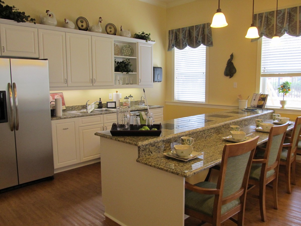 A well-lit kitchen with a central island, bar stools, and modern appliances.