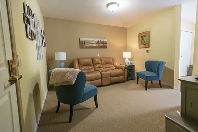 A cozy living room with a brown sofa, blue armchairs, and ambient lighting.