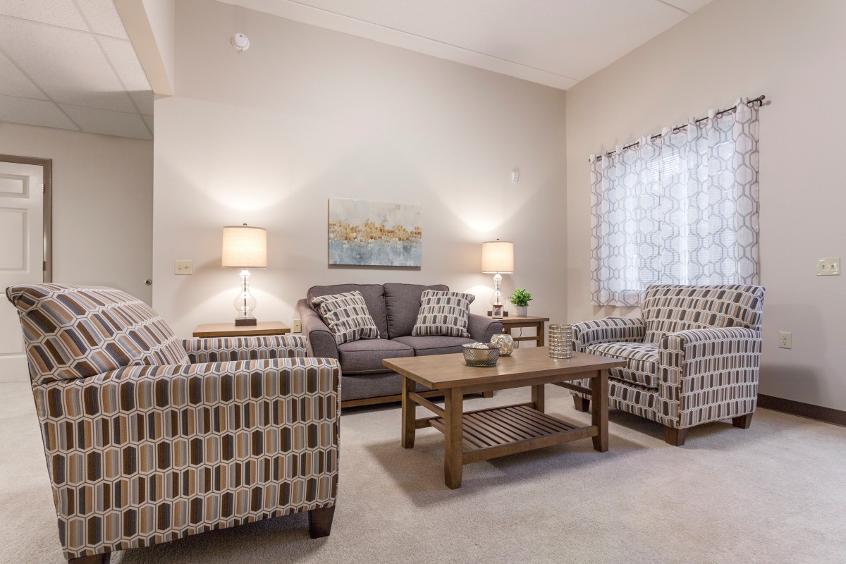 A cozy living room with a sofa, patterned armchairs, and warm lighting.