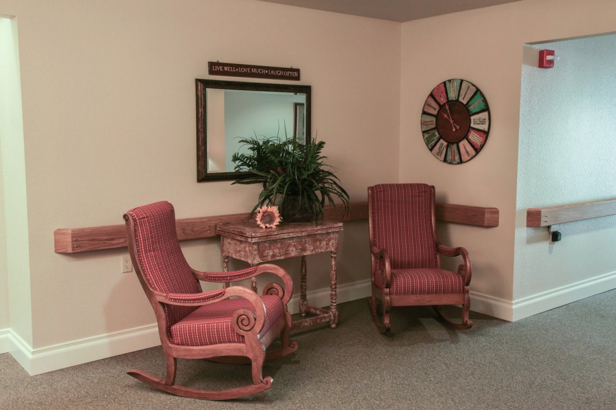 A cozy corner featuring two red rocking chairs, a decorative table with a plant, and a wall clock.