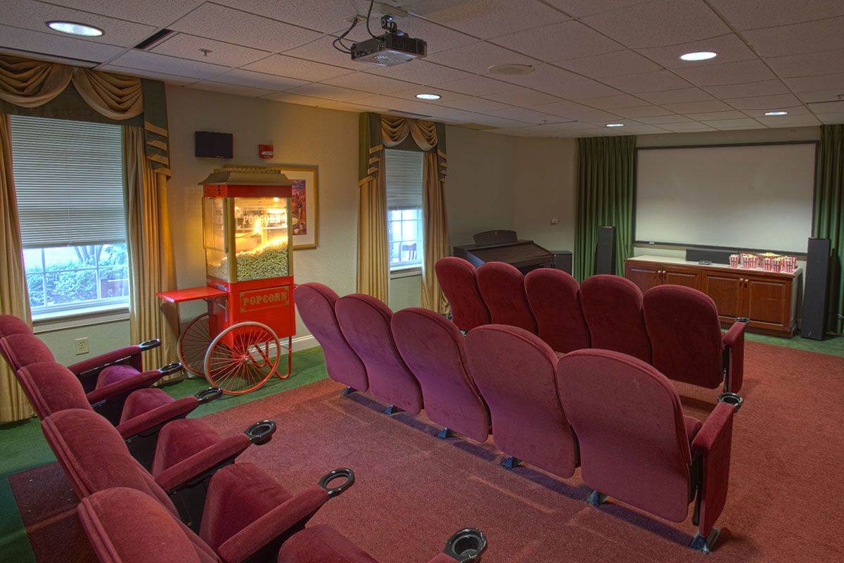 A cozy home theater setup with red seats, a projector, and a popcorn machine.