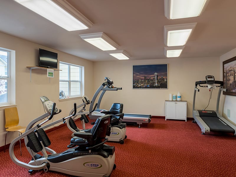 A small gym with workout equipment including treadmills and stationary bikes.