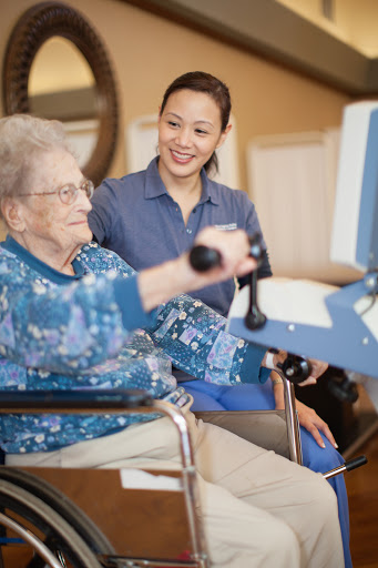 A caregiver assists an elderly woman with her physical therapy exercises, promoting health and well-being.