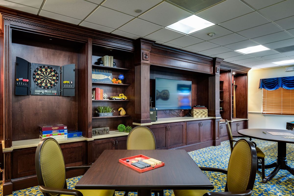 A modern lounge with a dartboard, television, and seating area.