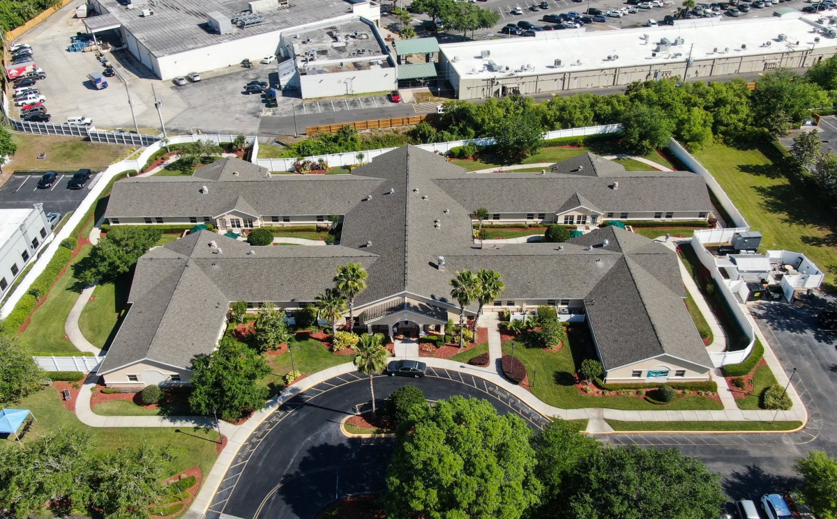 Aerial view of a large building complex surrounded by greenery and parking areas.