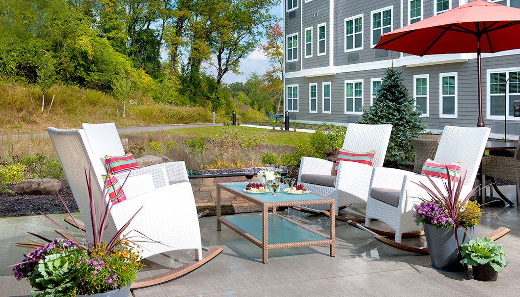 A cozy outdoor patio setup with comfortable chairs and a table in front of a modern building.