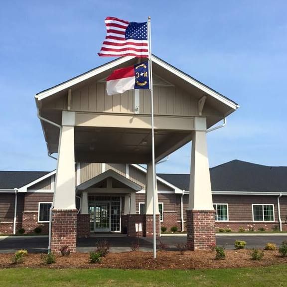 A building entrance with American and state flags flying.