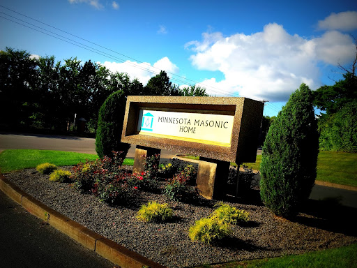 The entrance sign of a Masonic home, surrounded by well-maintained landscaping and a clear blue sky.