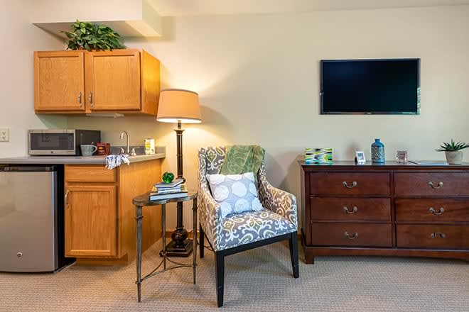 A cozy living room corner with an armchair, side table, and wall-mounted television.