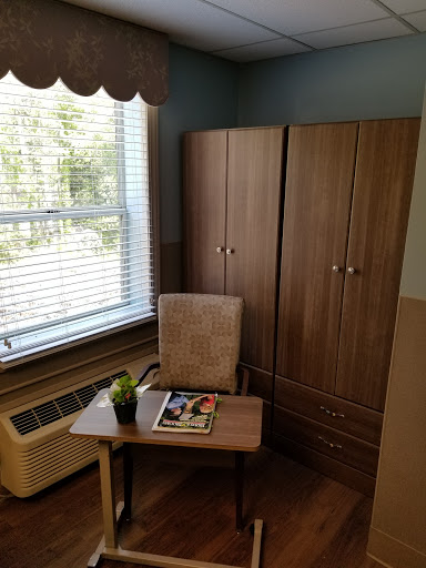 A cozy corner of a room featuring a desk, chair, and storage cabinet by the window.