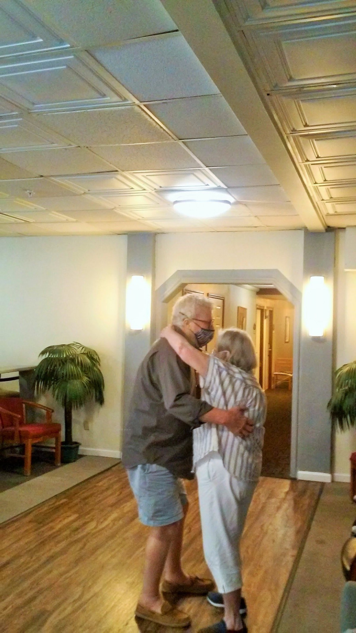An elderly couple dancing together in a warmly lit room.
