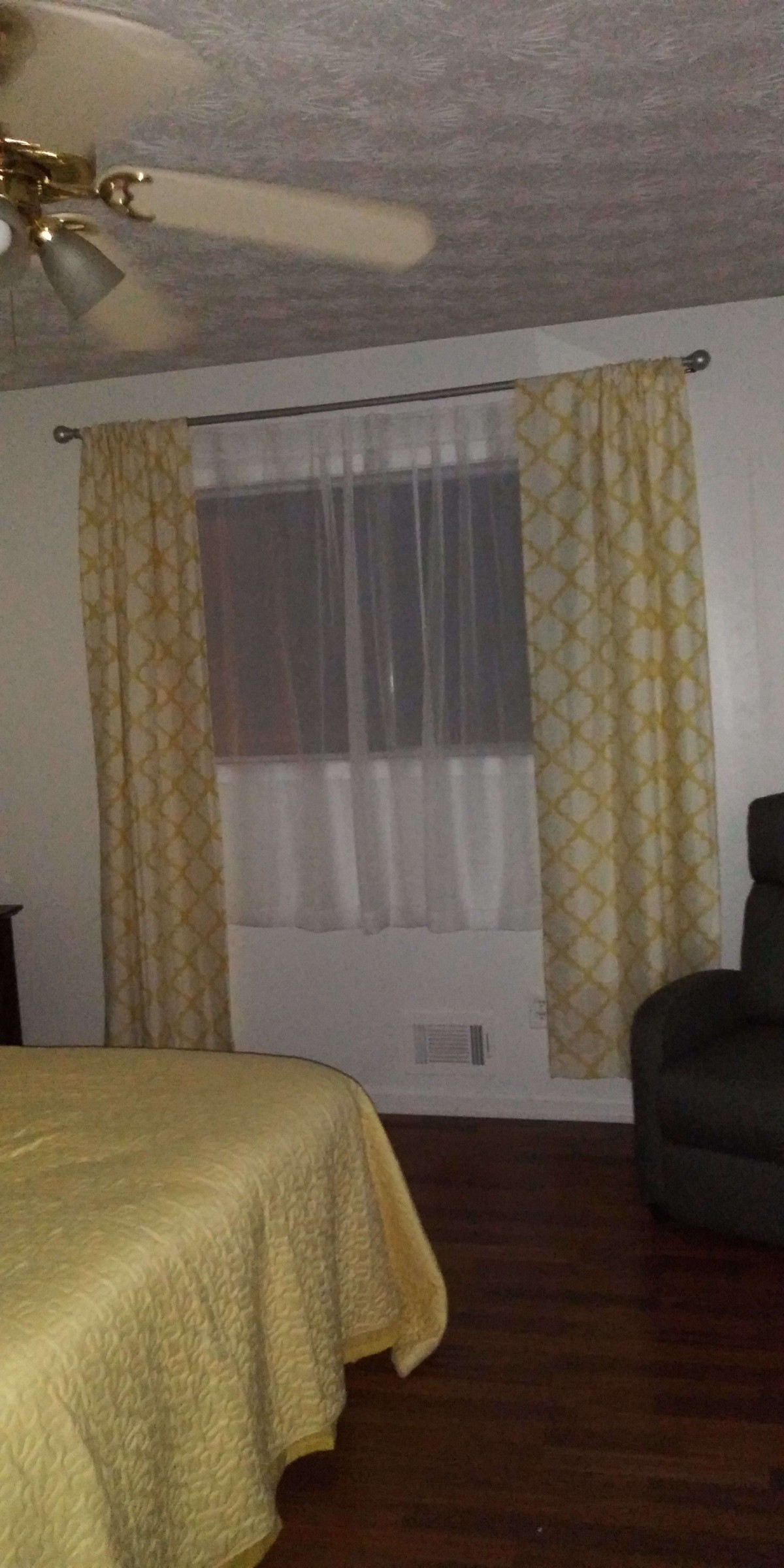 A bedroom with patterned yellow curtains, a window, and a piece of furniture.