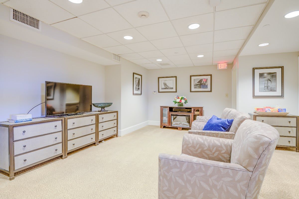 A cozy basement living area with a sofa, television, and decorative artwork on the walls.
