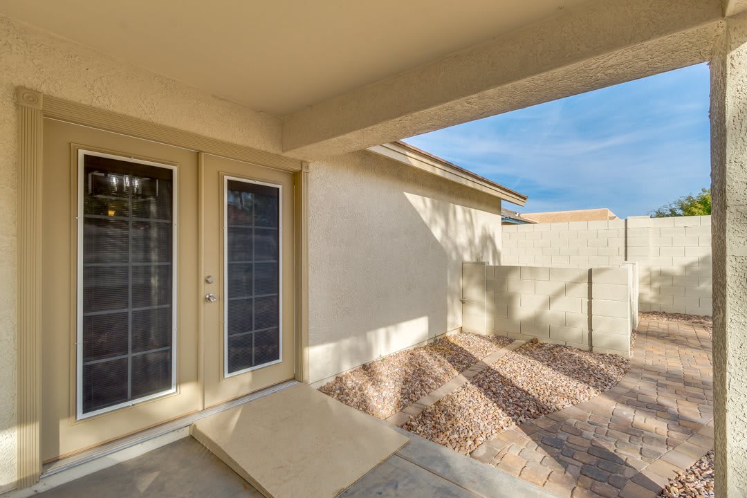 Sunny patio with French doors leading to a small backyard area.