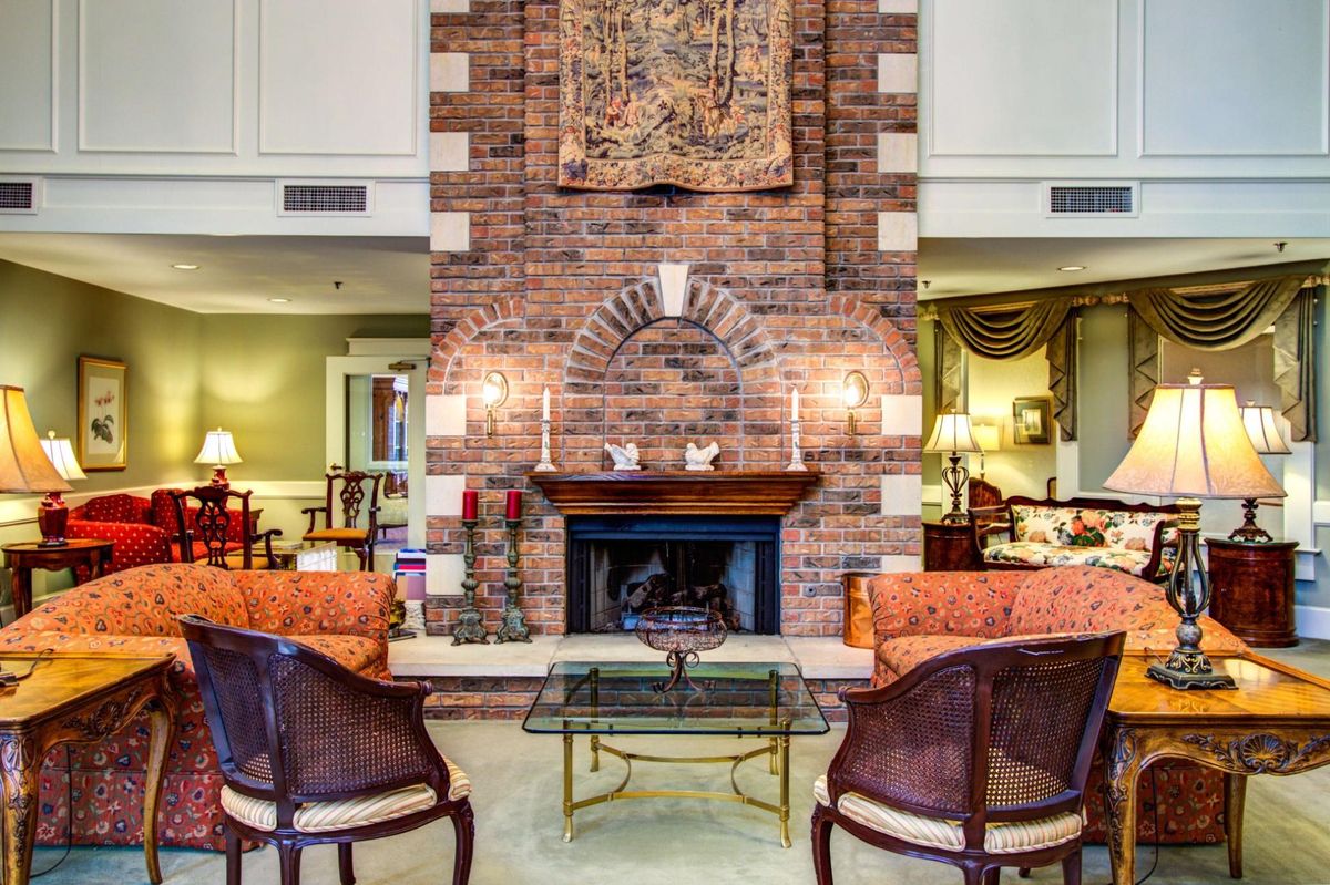 A cozy living room featuring a brick fireplace, elegant seating, and warm decor.