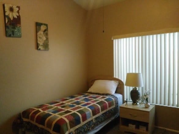 A simple bedroom with a single bed and nightstand.